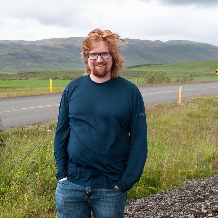 A photo of Leif standing in front of a small hill in Iceland.